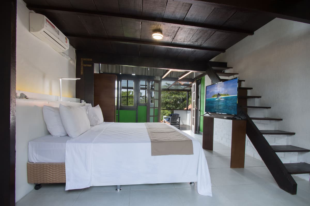 Une chambre à coucher comprenant un lit, un bureau, une chaise, un escalier et une vue sur l’extérieur.