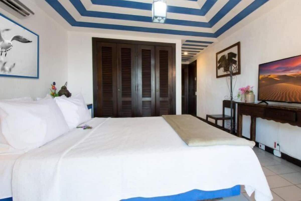 Une chambre d’hôtel comprenant un lit, une télévision, un bureau et une porte donnant sur une autre pièce.