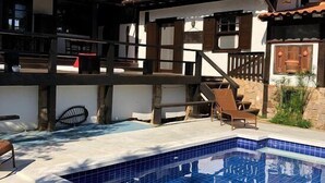 A two-story building with a swimming pool, outdoor seating, and a rustic architectural style. - Pousada do Adriano (Búzios)