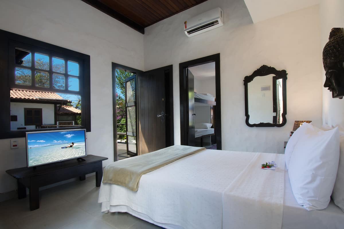 Une chambre d’hôtel avec un lit, une télévision et une vue sur la mer par la fenêtre.