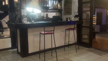 Zona de bar con mostrador, taburetes y un cartel que prohíbe fumar.