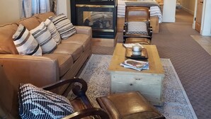A cozy living room with a leather sofa, a wooden coffee table, and a fireplace.