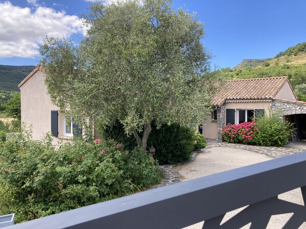 A house with a stone facade, a tiled roof, and a garden with flowering plants.