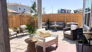 Un espace extérieur aménagé en terrasse, avec des meubles en osier, un canapé blanc et une plante en pot.