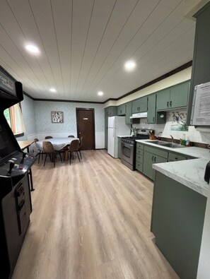 A kitchen with a dining table, chairs, a stove, and cabinets.
