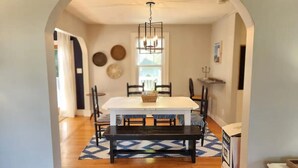 A dining area with a white table, black benches, and a patterned rug. - Vacation Starts Now! Pet friendly, beach fun 5 min away! (New London)