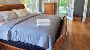 A bedroom with a bed, dresser, and a view of the outdoors through a door. - Vacation Starts Now! Pet friendly, beach fun 5 min away! (New London)