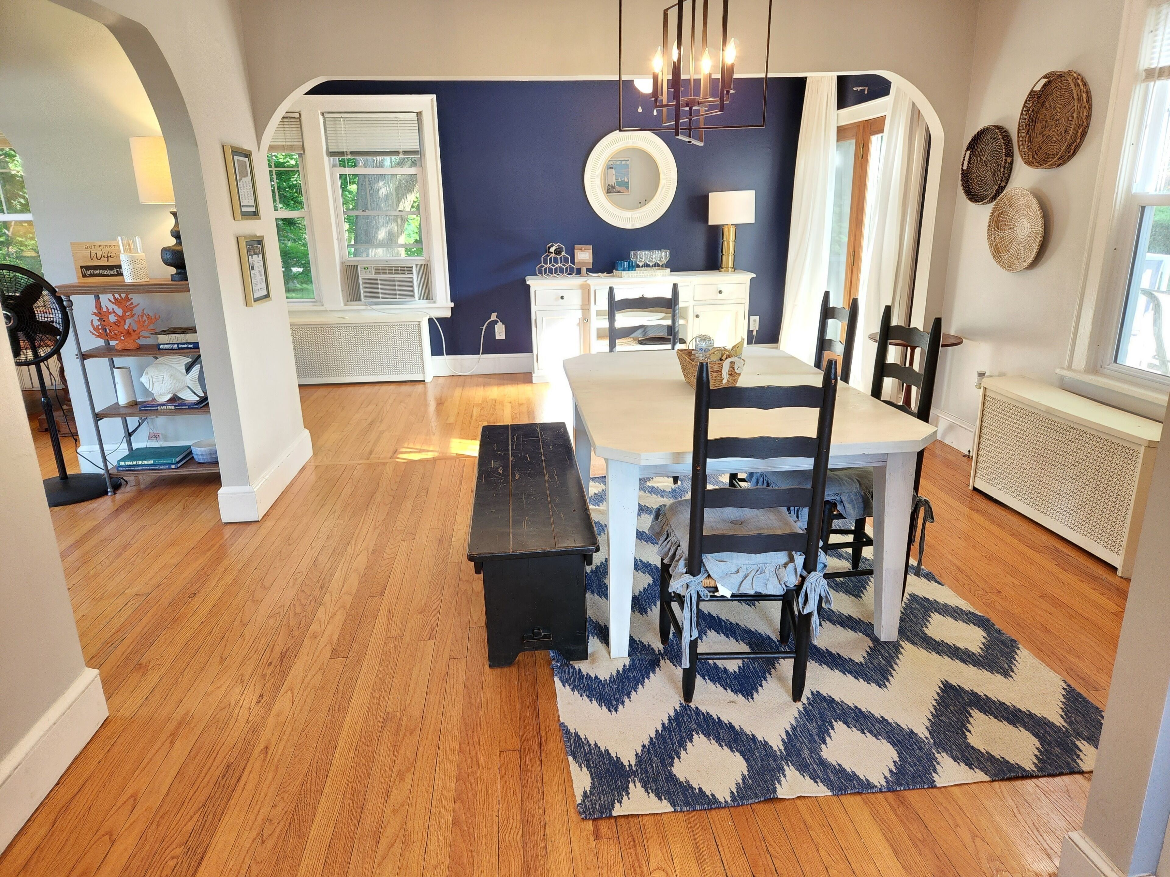 A dining area with a table, chairs, and a bench. There is a patterned rug on the floor.