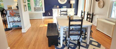 A dining area with a table, chairs, and a bench. There is a patterned rug on the floor.