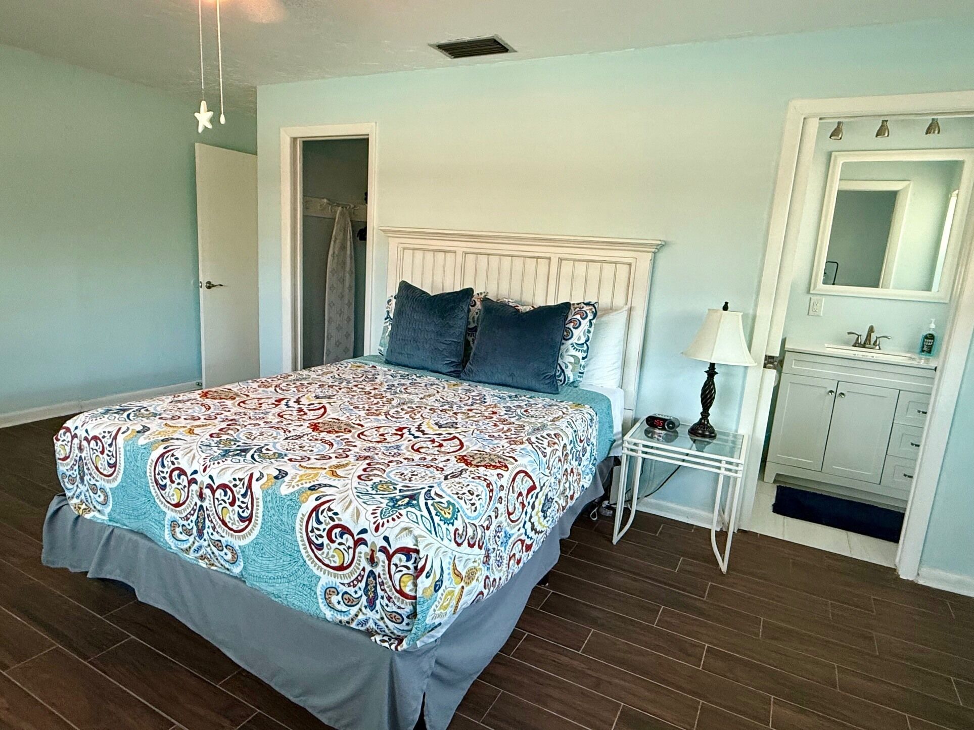A bedroom with a bed, a nightstand, a mirror, and a bathroom cabinet.
