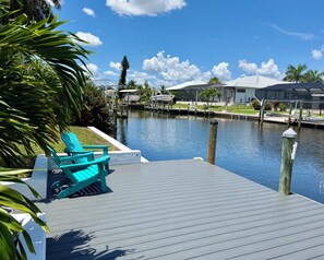 A dock with boats, a clear sky, and a water body. - Beautiful canal view, direct Gulf access, gorgeous heated pool! (Cape Coral)