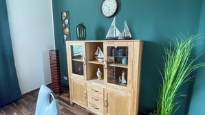 A wooden cabinet with glass doors, a clock, and decorative items on teal walls.
