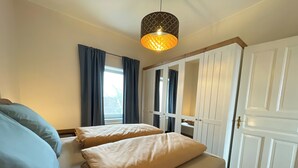 A bedroom with two beds, a wardrobe, and a hanging light fixture.