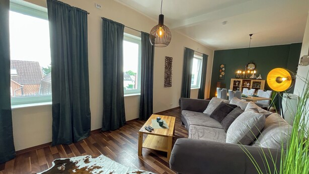 A modern living room with a sectional sofa, wooden flooring, a coffee table, and a cowhide rug.