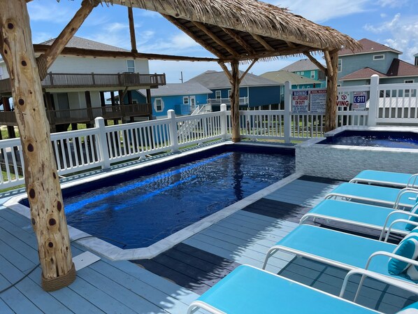 A pool area with blue water, wooden deck, and white railings.