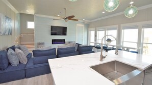 A modern kitchen with a marble countertop, a built-in sink, and pendant lights.