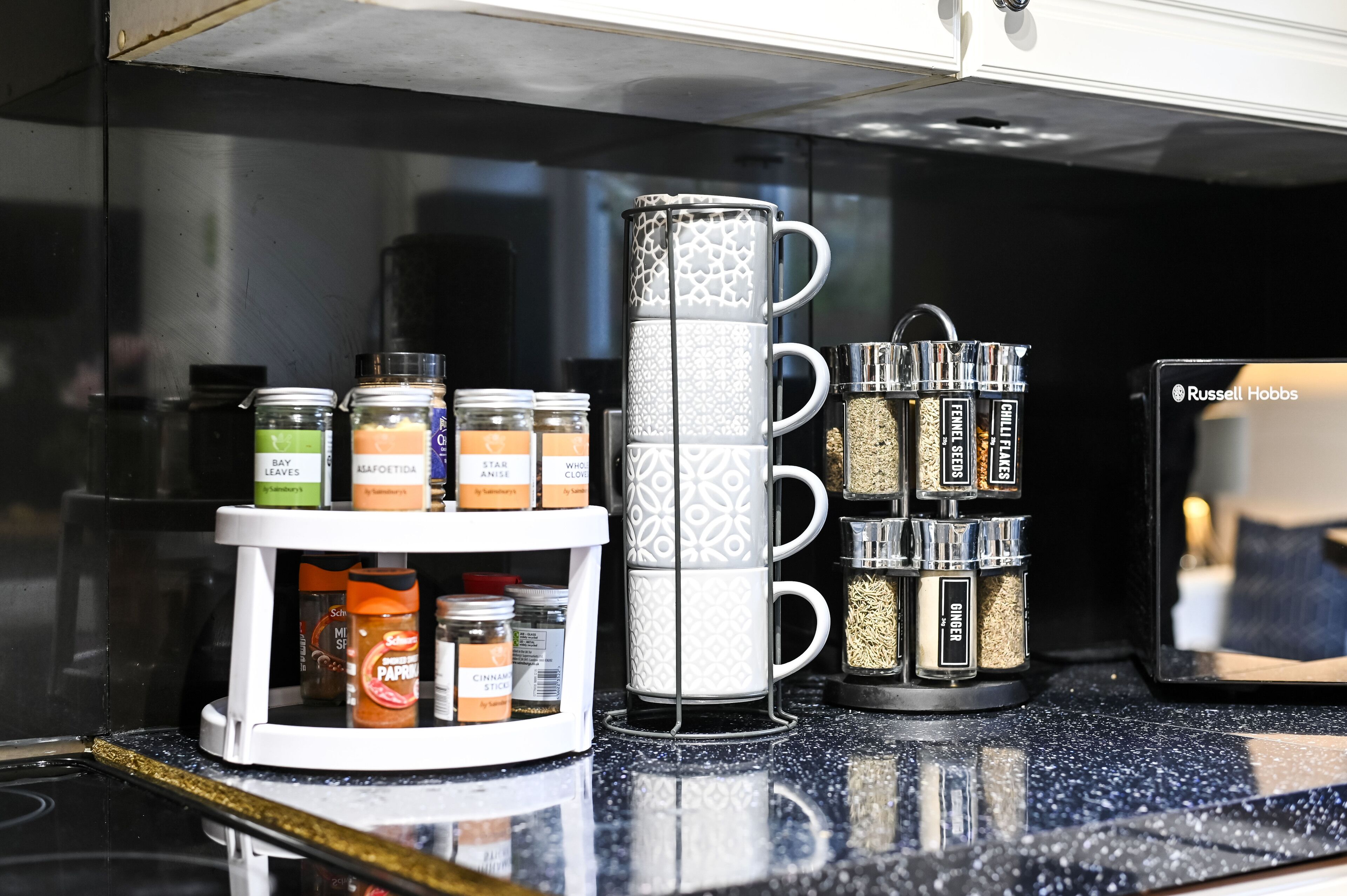 A kitchen counter with a coffee maker, a spice rack, and various spice jars.