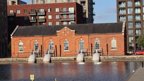 A brick building with large windows and a flat roof, situated next to a body of water. - Riverside Townhouse with private Garden (London)
