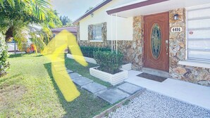 Uma casa com fachada de pedra, uma porta de madeira com painel de vidro e o número 4496 na parede.
