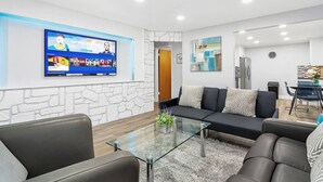 Uma sala de estar moderna com sofá, mesa de centro e televisão de tela plana fixada na parede.