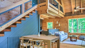 Un intérieur en bois comprenant un coin repas, un escalier et un canapé, le tout dans un décor évoquant une cabane.