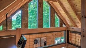 Une pièce mansardée en bois, dotée de grandes fenêtres et d’une rambarde en bois.