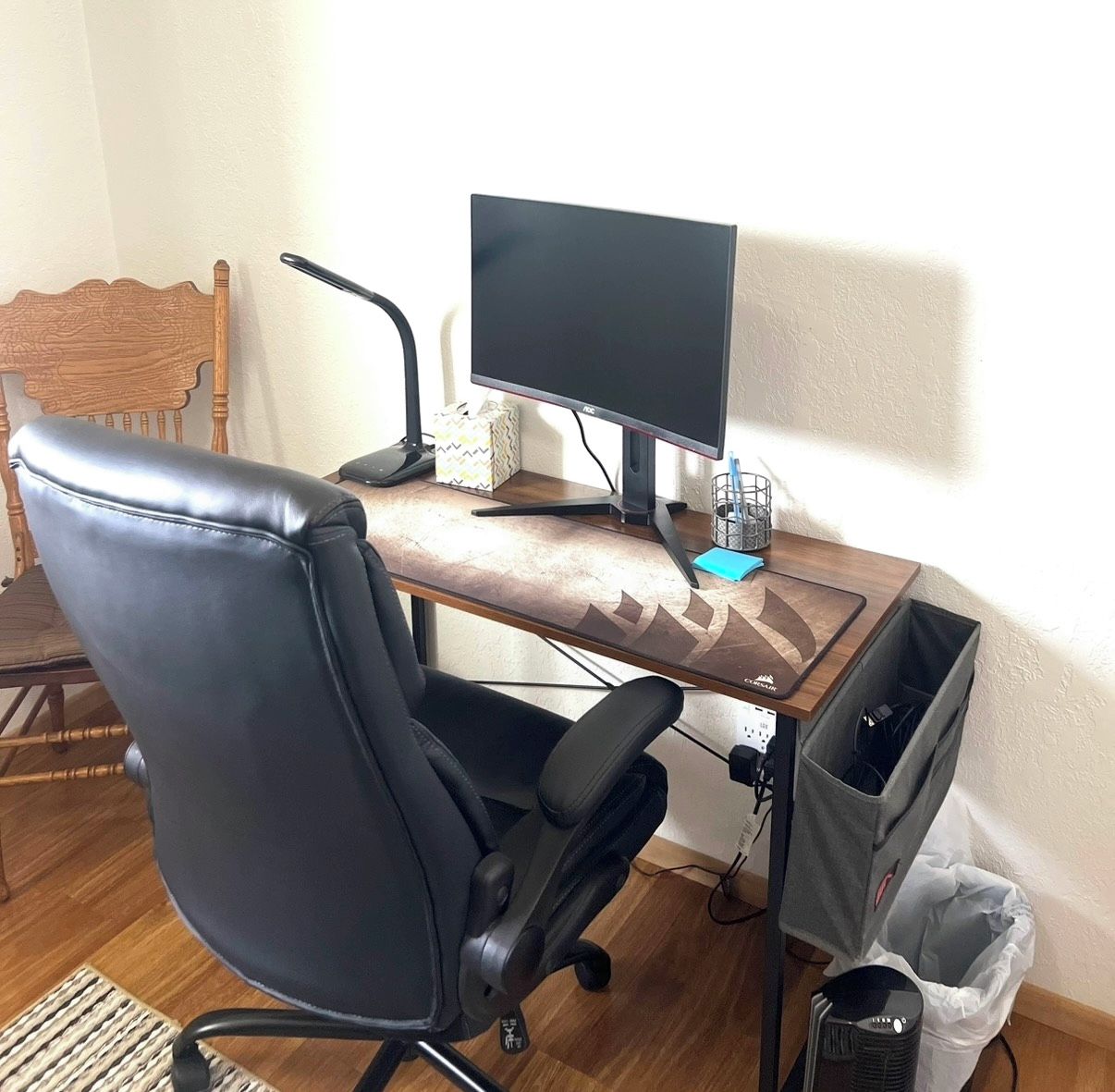 A home office setup with a desk, computer, chair, and storage bins.
