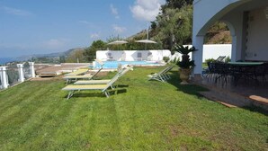 A pool area with lounge chairs and umbrellas, a covered seating area, and a view of the sea. - Tropea, Appartamenti Borgo Panoramico N .10 (Tropea)