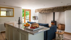 A modern kitchen with a central island, a stone fireplace, and a cozy seating area. - Snowdonia Cottage with Stunning views of Bala lake and mountains (Llangower)
