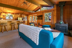 A cozy cabin interior with a large bed, wooden walls, a kitchen area, and a fireplace. - Charming Hot Tub Cabin (Idyllwild-Pine Cove)