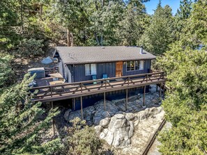 A cabin with a deck, surrounded by forest.