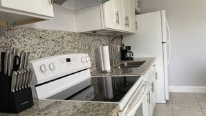 A kitchen with granite countertops, white cabinets, a white stove, and a refrigerator. - Welcome to this stylish and spacious luxury suite (Fort Lauderdale)