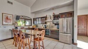 Eine moderne Küche mit Marmorarbeitsplatte, Holzkohle, einem Edelstahl-Kühlschrank und Holzschränken.