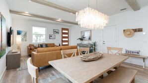 Un salon moderne avec une table à manger en bois, un canapé et un luminaire suspendu.
