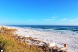 A beach with a sandy shore, a few people, and a clear blue sky.