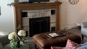 Una sala de estar con chimenea, televisión y un reloj en la pared.