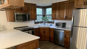 Una cocina moderna con armarios de madera, electrodomésticos de acero inoxidable y un ventanal que proporciona luz natural.