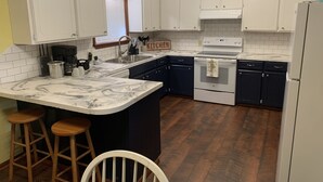 A kitchen with white cabinets, a marble countertop, a stove, and wooden stools. - Minutes from Beautiful broken bow lake  (Broken Bow)