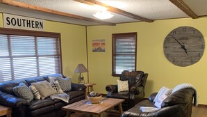 A cozy living room with two leather sofas, a wooden coffee table, and a large wooden clock on the wall. - Minutes from Beautiful broken bow lake  (Broken Bow)