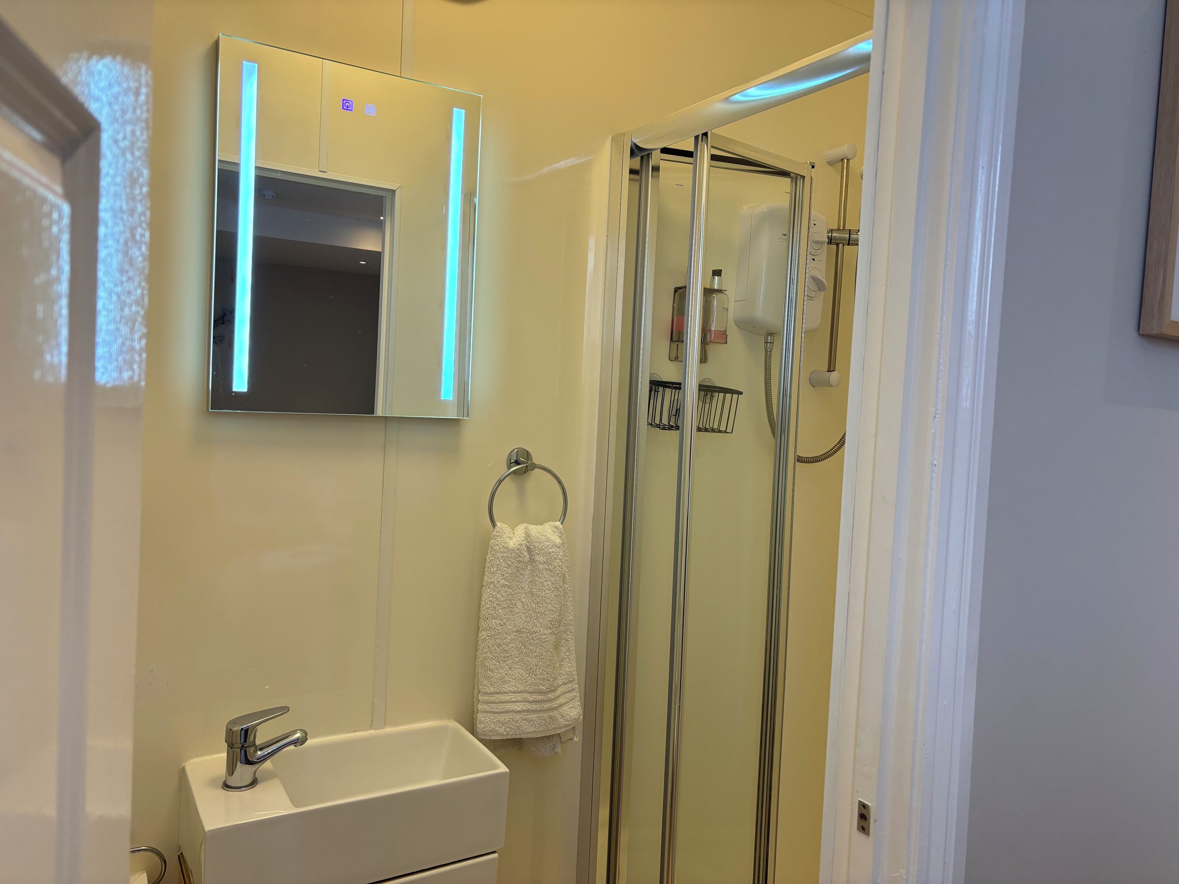 A bathroom with a white sink, a mirror, and a glass shower enclosure.