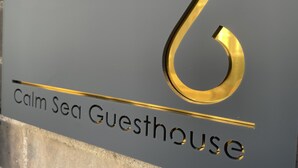 Un segnale con il numero 6 e la scritta 'Calm Sea Guesthouse', che indica il nome della struttura e il numero della stanza.
