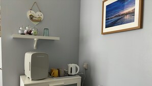 Una kitchenette con frigorifero SUBCOLD, bollitore e macchina del caffè su un mobile bianco.