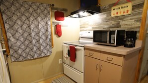 Cocina compacta con microondas, cafetera y un cartel que indica un espacio para un descanso con café.