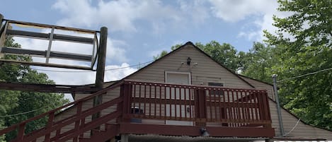 A wooden building with a balcony, a metal staircase, and a white picket fence.