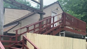 Una escalera de madera con barandas rojas que lleva a un espacio al aire libre cubierto.