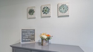 A reception desk with a welcome sign, three framed succulent plants, and a vase with flowers.