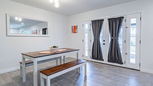 A room with a wooden dining table, bench, and a large mirror on the wall.