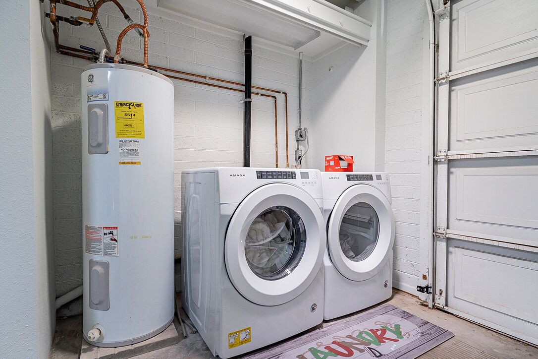 A laundry area with a water heater, two washing machines, and a door.