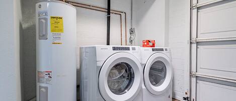 A laundry area with a water heater, two washing machines, and a door.