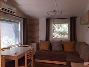 A compact living space with a sofa, a small table, and a window with curtains.